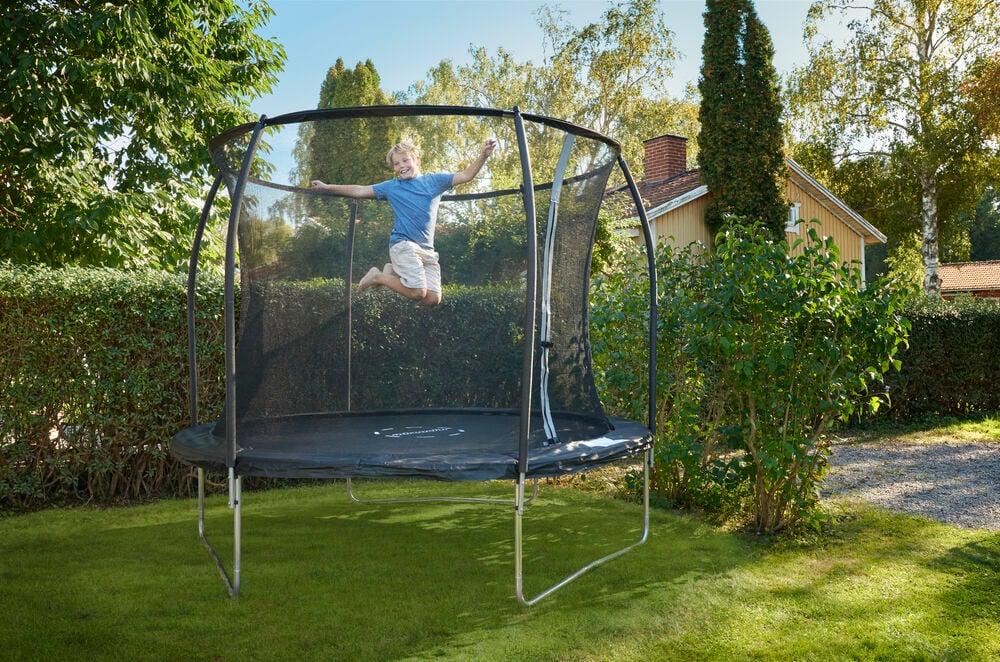 Person som hopper på trampoline med sikkerhetsnett.