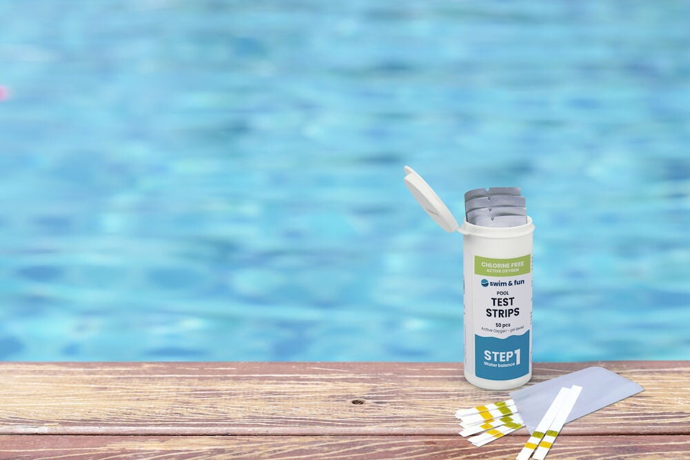 Burk med teststickor och bruksanvisning vid poolkant.
