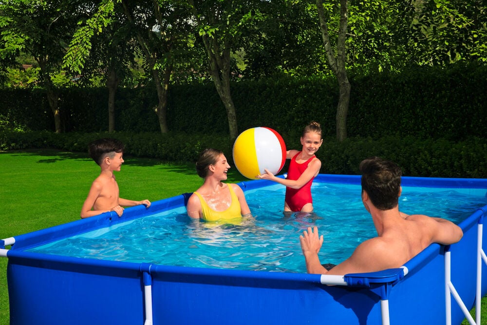 Fire personer bader i rektangulært hagebasseng utendørs.