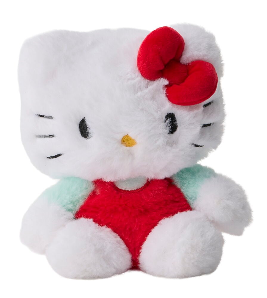 Valkoinen Hello Kitty pehmolelu, punainen rusetti, mustat silmät, keltainen nenä, punainen vartalo ja mintunvihreät hihat.