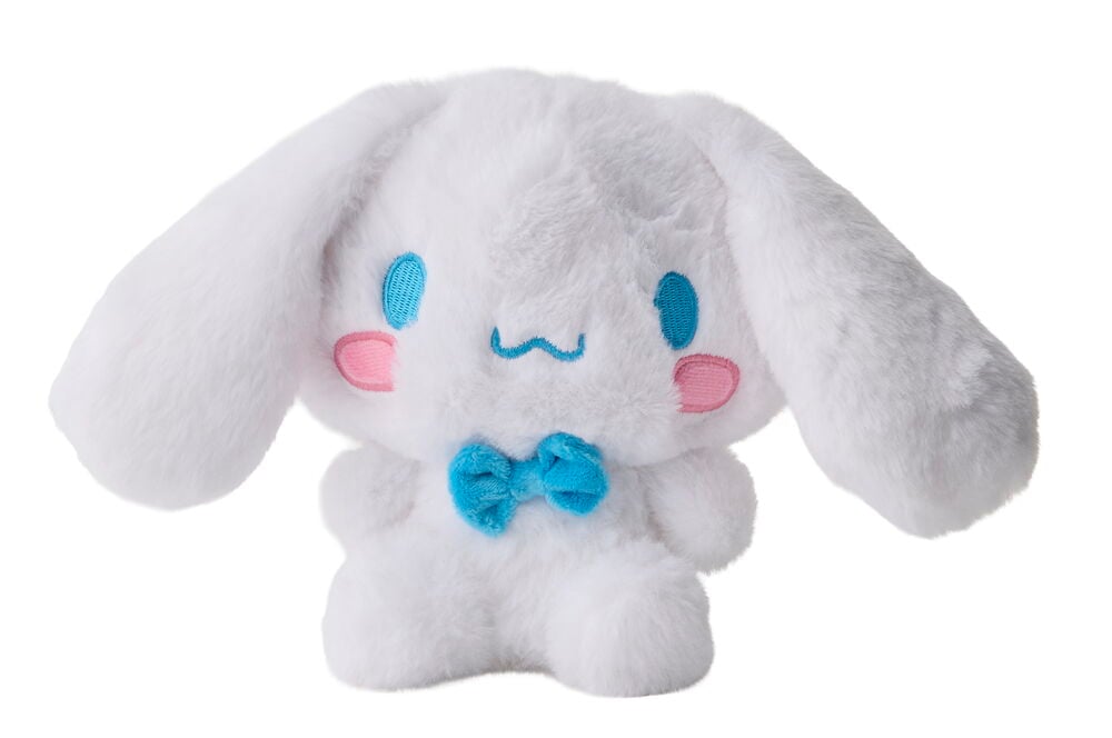 Valkoinen pörröinen Cinnamoroll pehmolelu pitkillä korvilla, sinisillä silmillä, vaaleanpunaisilla poskilla, sinisellä suulla ja sinisellä rusetilla.