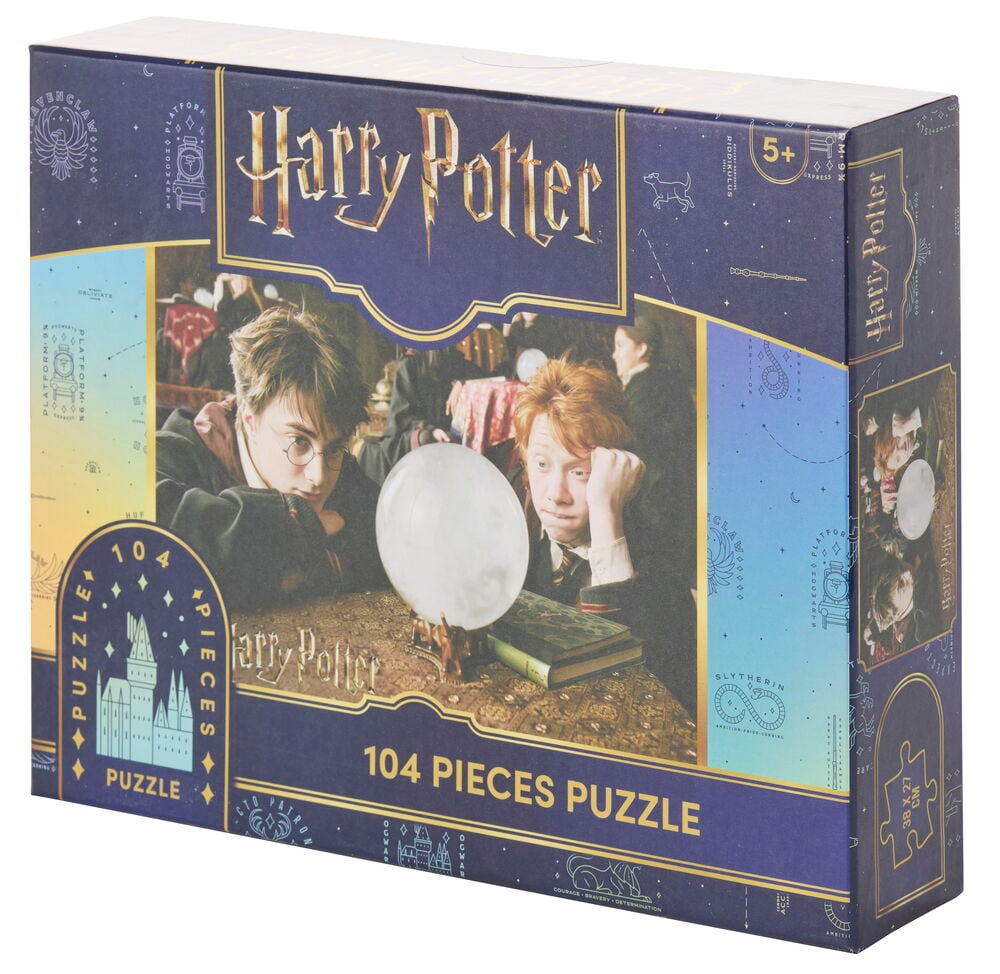Eine rechteckige dunkelblaue Puzzle Harry Potter 104 Teile Schachtel mit einer Filmszengrafik auf der Vorderseite.