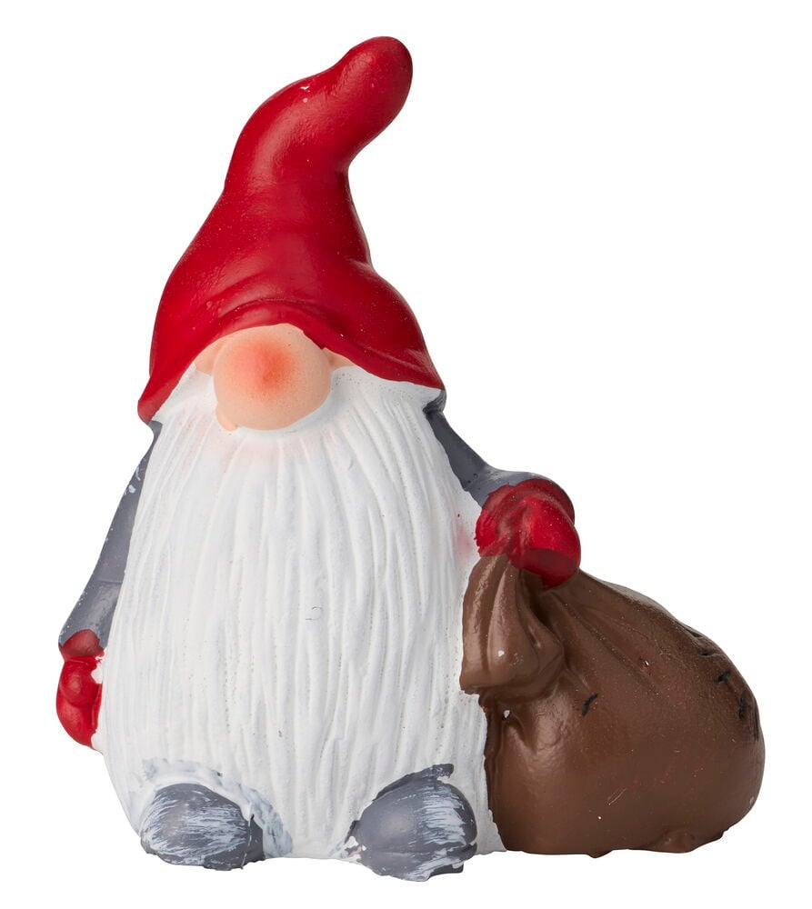 En jul-dekorationsfigur av en tomte med röd hatt, vitt skägg, grå kläder och en brun säck.