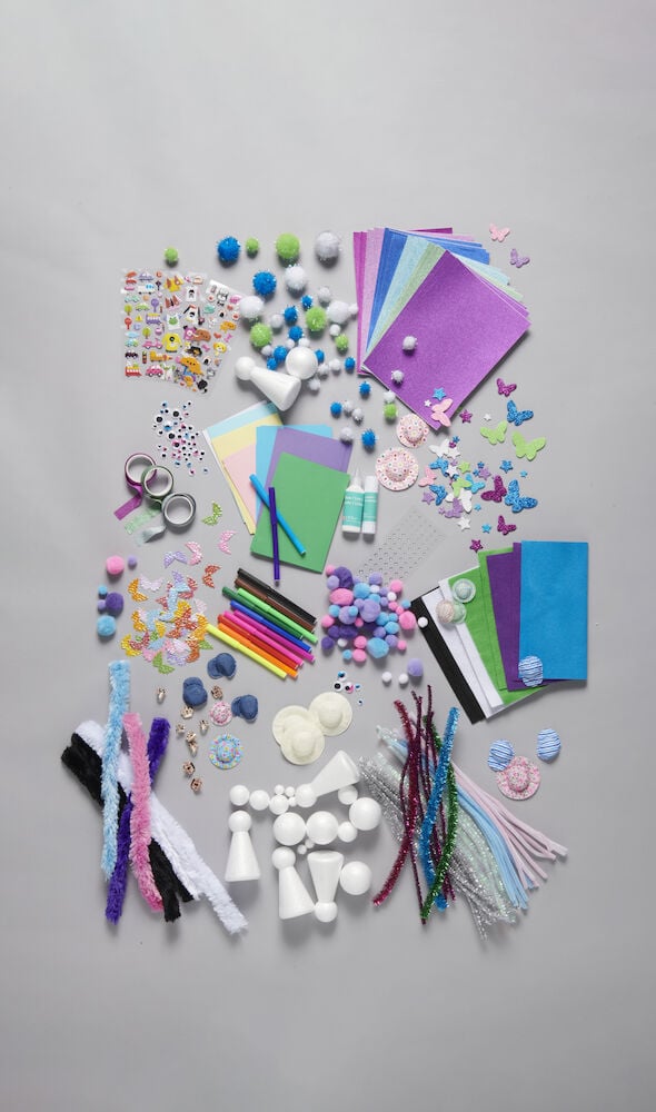 Pyssellåda med papper, piprensare, färgpennor och dekorationer.