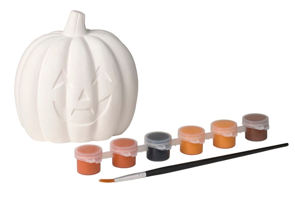 En vit keramisk Halloween-pumpa med snidat ansikte, sex färgburkar och en pensel.