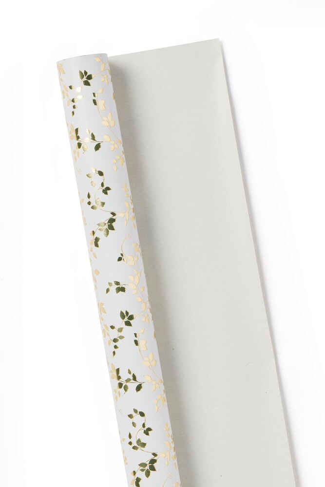 En rulle vitt presentpapper med gyllene blad.