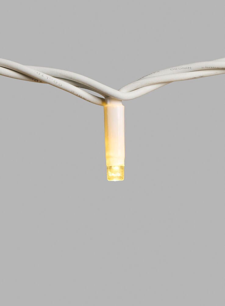 Nærbilde av en varmhvit LED-lampe fra en hvit Lysslynge Outdoor LED Light System med hvite ledninger.