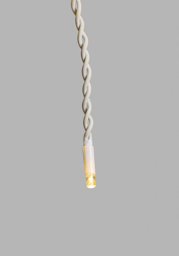 Nærbilde av en varmhvit Lysgardin Outdoor LED Light System med en vridd hvit kabel.