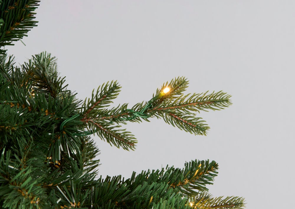 Nærbilde av et grønt kunstig juletre med integrerte varmhvite LED-lys.