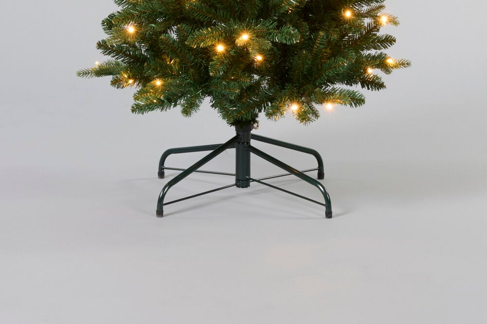 Juletre Trysil PVC/PE 150 LED med grønne grener og varmgule lys på et mørkegrønt metallstativ.