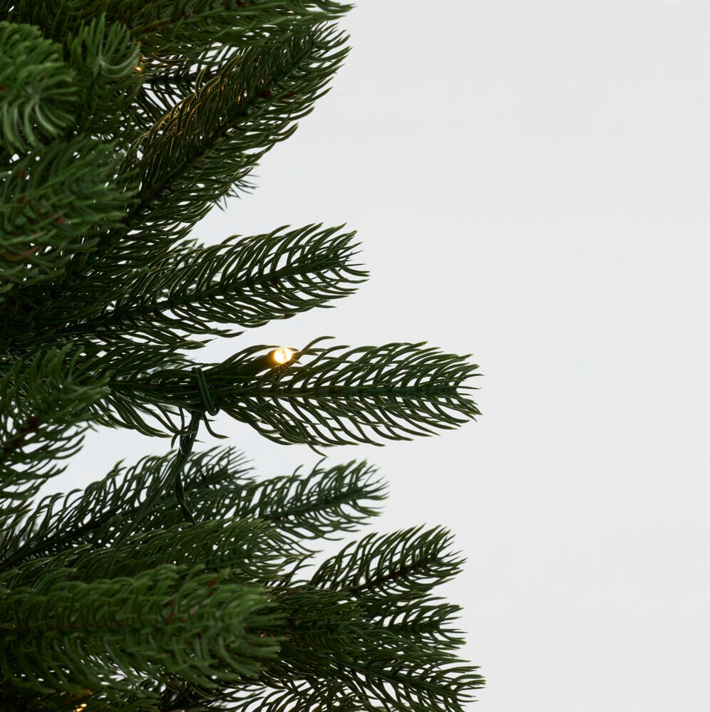 Närbild på gröna konstgjorda juldekorationer med små varma LED-lampor.