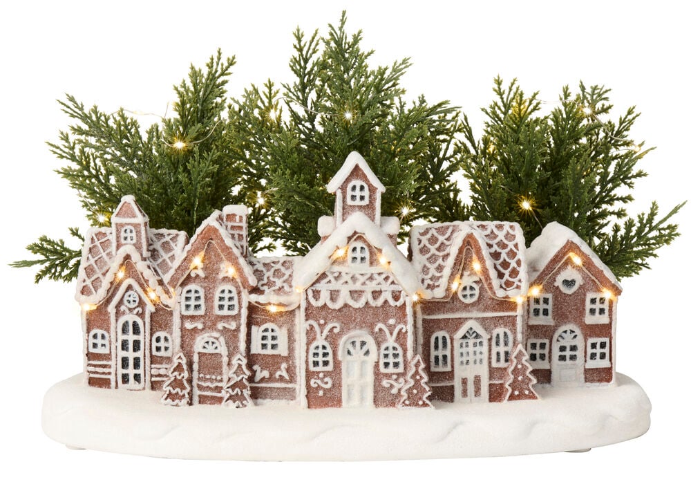 Warmweiß Batteriebetrieben mit Timer: Ein Lebkuchen-Dorf mit beleuchteten Häusern und grünen Bäumen auf einem Schneesockel.