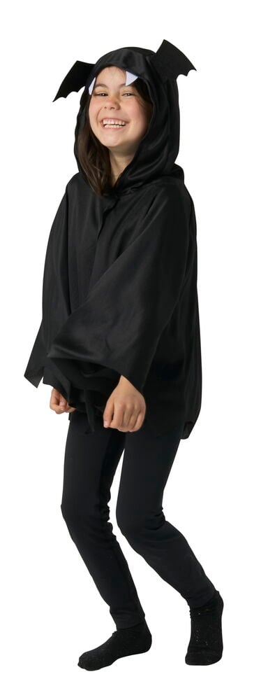 Ett barn bär svart Maskeradset, barn One Size fladdermusdräkt med huggtänder, svarta leggings och strumpor.