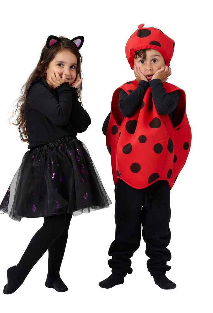 Rød Halloweenponcho, barn One size med sorte prikker og hatt. Et annet barn har på seg svart kattkostyme.