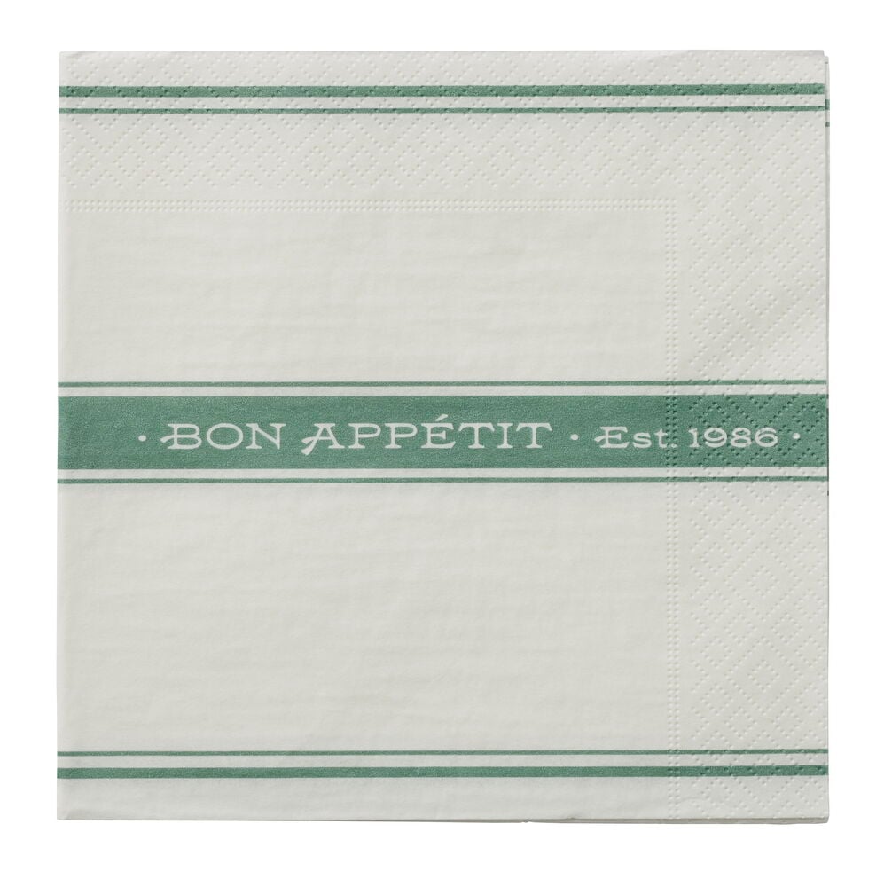 En stabel hvite papirservietter med grønne striper og teksten "BON APPÉTIT • Est. 1986".