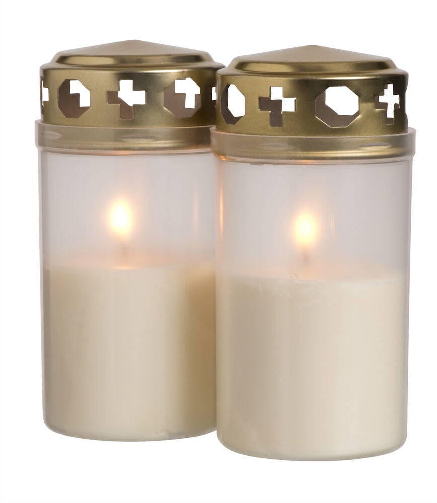 Kaksi valkoista hautakynttilää, joissa on kultainen kansi, sytytettyinä.