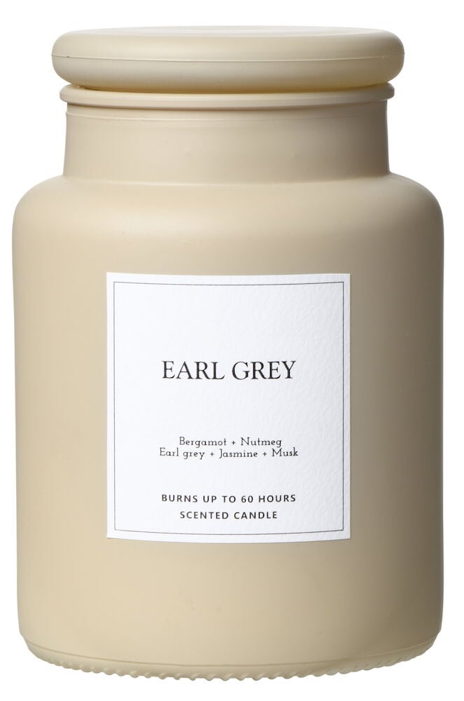 Beige duftlys i glasskrukke med tilhørende lokk.