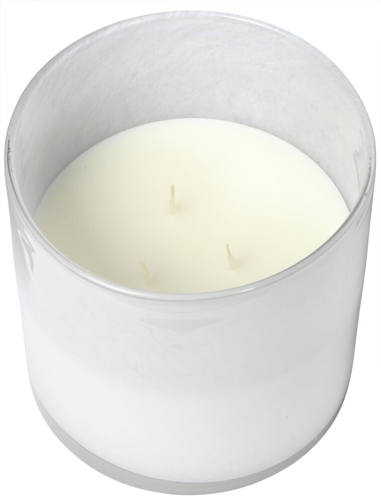 Stort vitt ljus i genomskinlig glasbehållare.