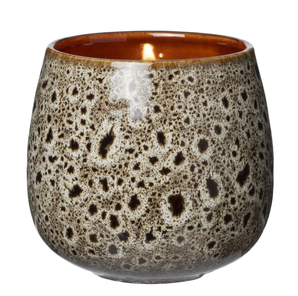 Brunt doftljus i mönstrad keramikkopp med låga.