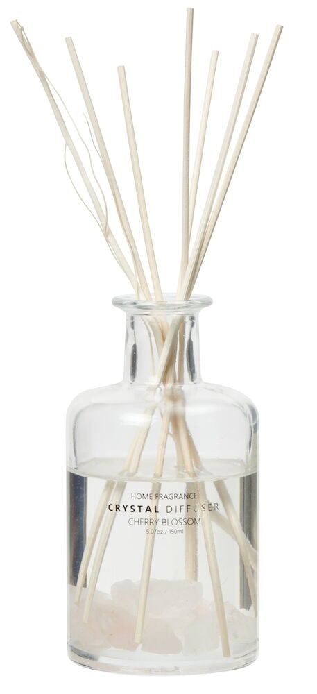 Glassflaske med hvite rottingpinner og rosa steiner.