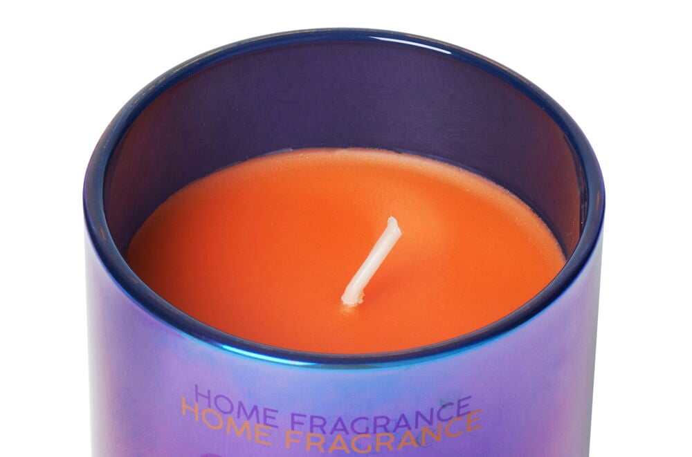 Eine orange Duftkerze in einem perlmuttfarbenen Glas.