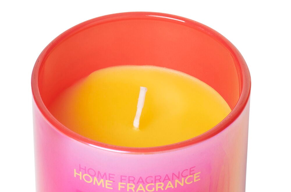 Gelbe Duftkerze in rosa Glasbehälter.