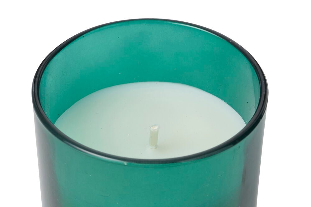 Närbild av ett vitt Doftljus Merry i en mörkgrön glashållare med synlig veke.