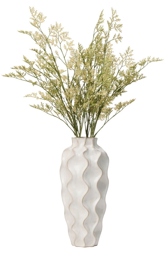 En lång, vit vågig vas innehåller en bukett Risp 75 cm Vit blommor.