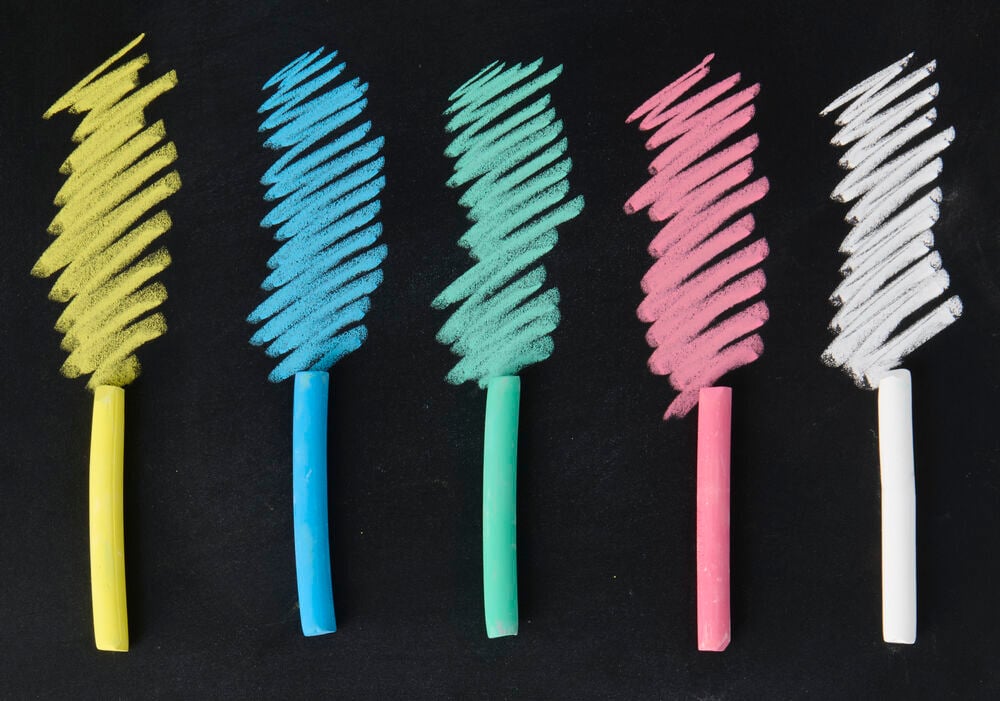 Fünf Elsaform Kids Tafelkreide in Gelb, Blau, Grün, Rosa und Weiß, die auf Schwarz zeichnen.