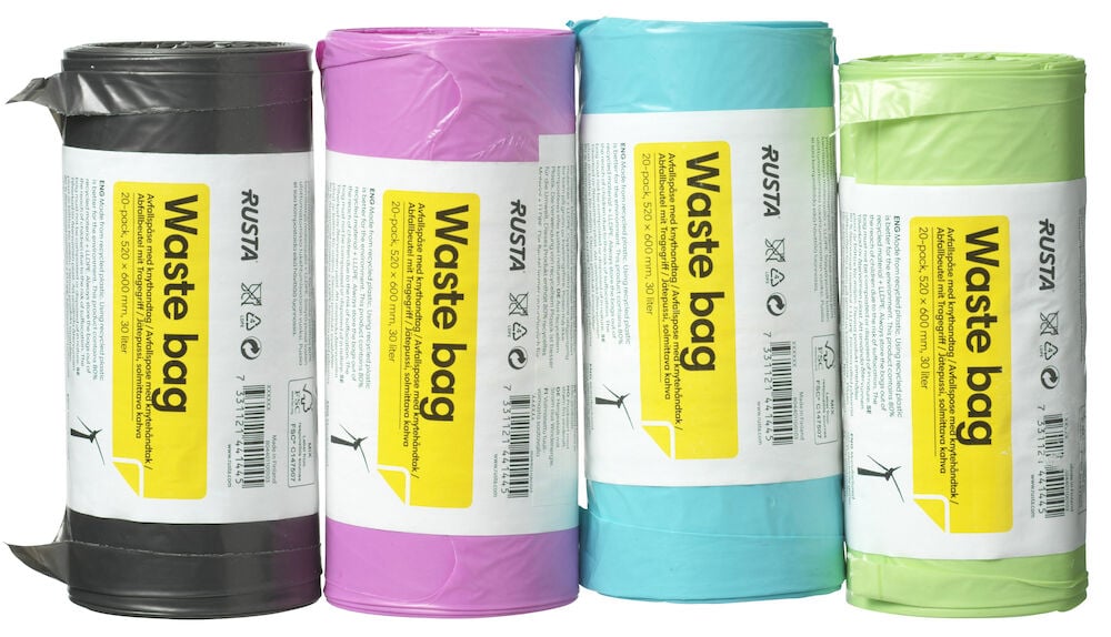 Vier Rollen neonfarbene Müllbeutel mit Griffen.