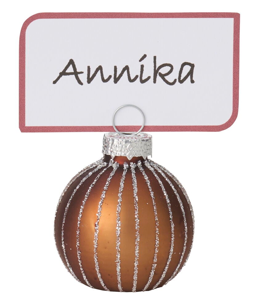 Ruskea Paikkakorttipidike Joulukoriste, jossa on hopeaglitterraitoja, pitää valkoista nimikorttia.