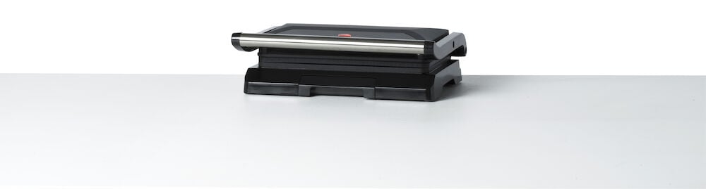 Musta monitoimigrilli, jossa hopeiset kahvat valkoisella pinnalla.