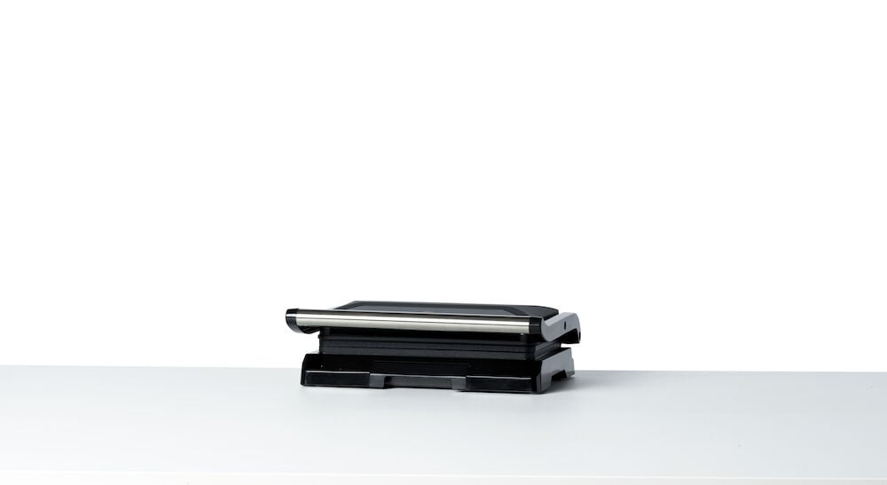 Musta monigrilli, jossa on suljettu kansi valkoisella pinnalla.