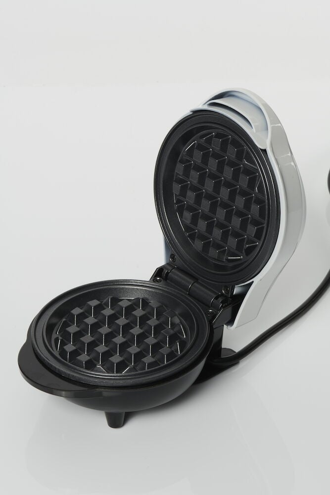 Öppet belgiskt våffeljärn med svart nonstick-yta.