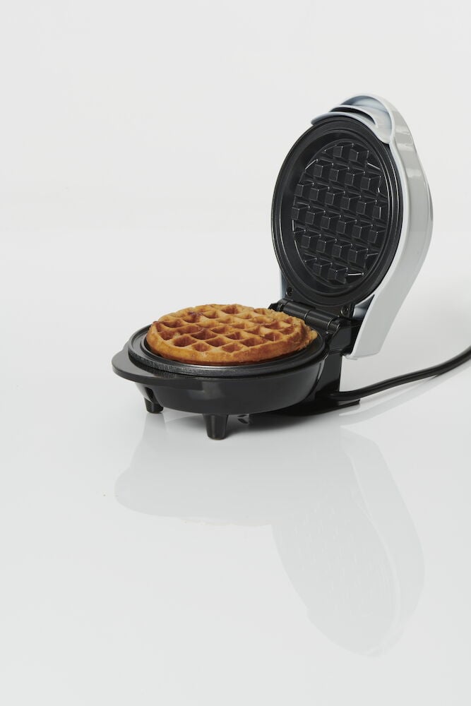 Ett öppet belgiskt våffeljärn med nygräddad våffla.