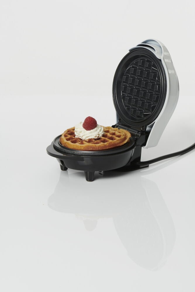 Öppet belgiskt våffeljärn med våffla och grädde.