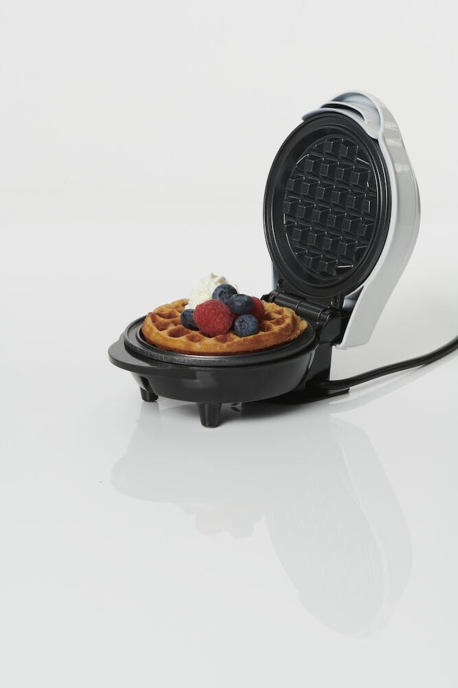 Belgiskt våffeljärn med färdig våffla och bär.