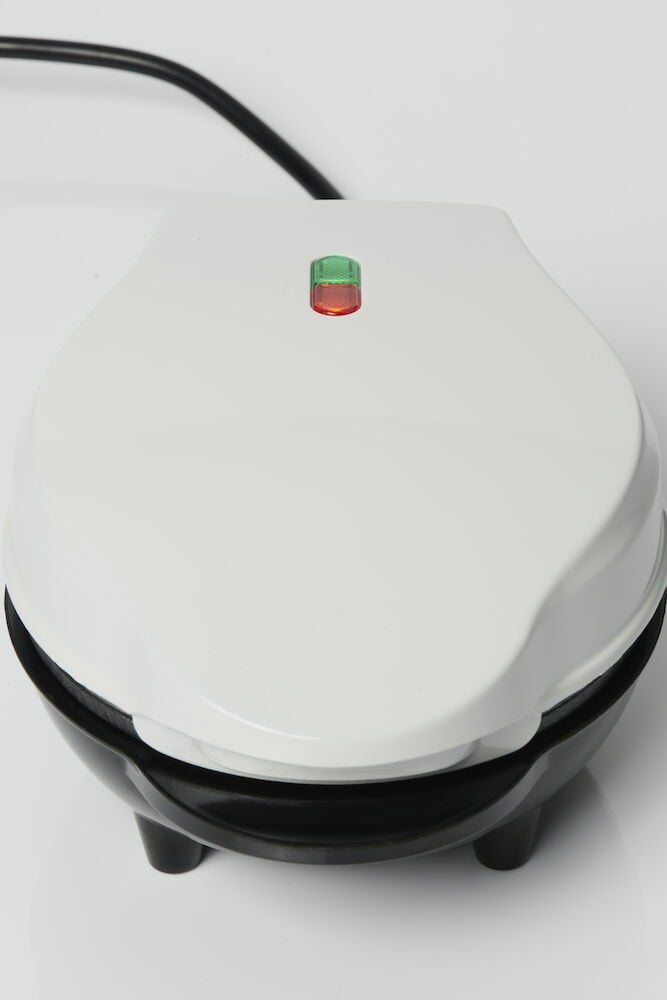 Vitt belgiskt våffeljärn med indikatorlampor.