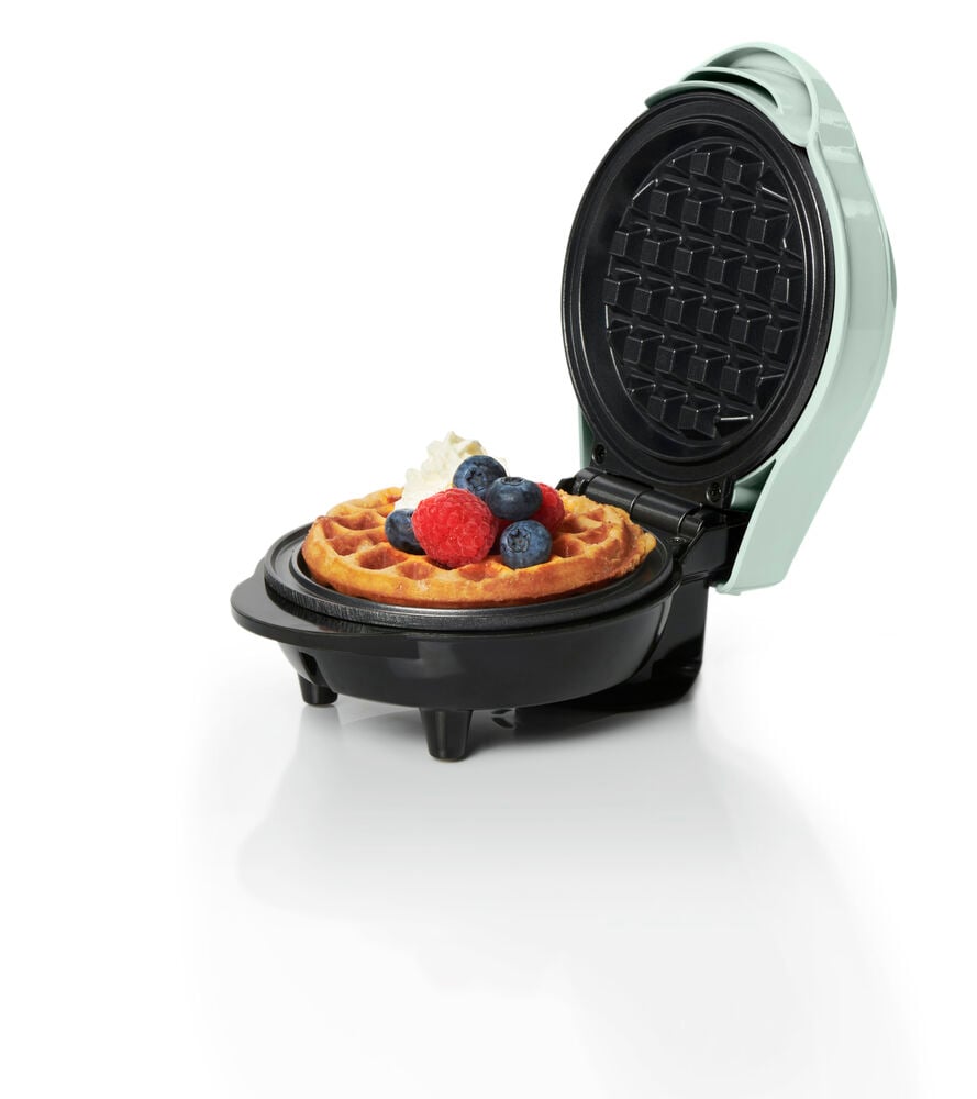 Öppet våffeljärn med färdig våffla och bär.