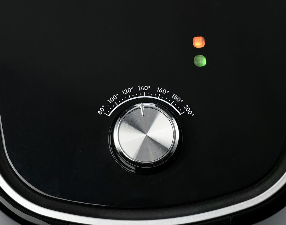 Rund svart vred med temperaturangivelser och två lampor.