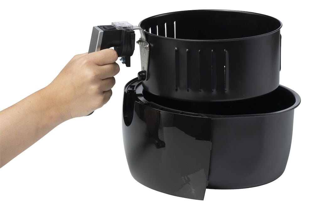 Hand håller i insats till svart airfryer.