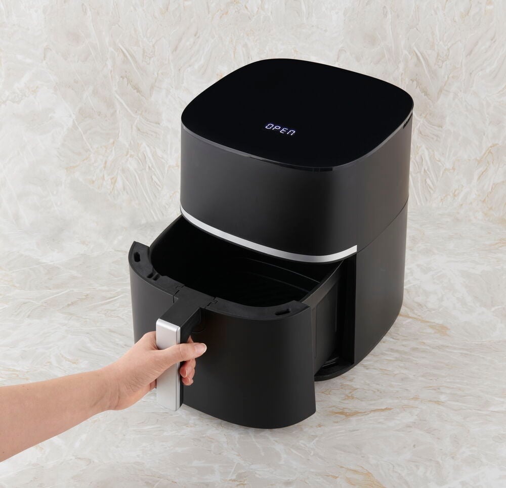 En matt svart airfryer med utdragen korg.