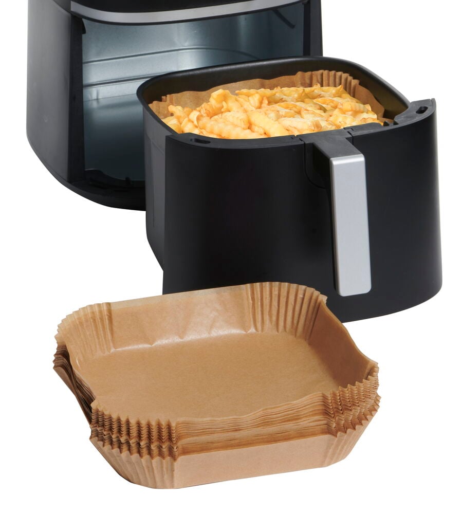 Fyrkantiga airfryer-papper i hög stapel framför fritös.