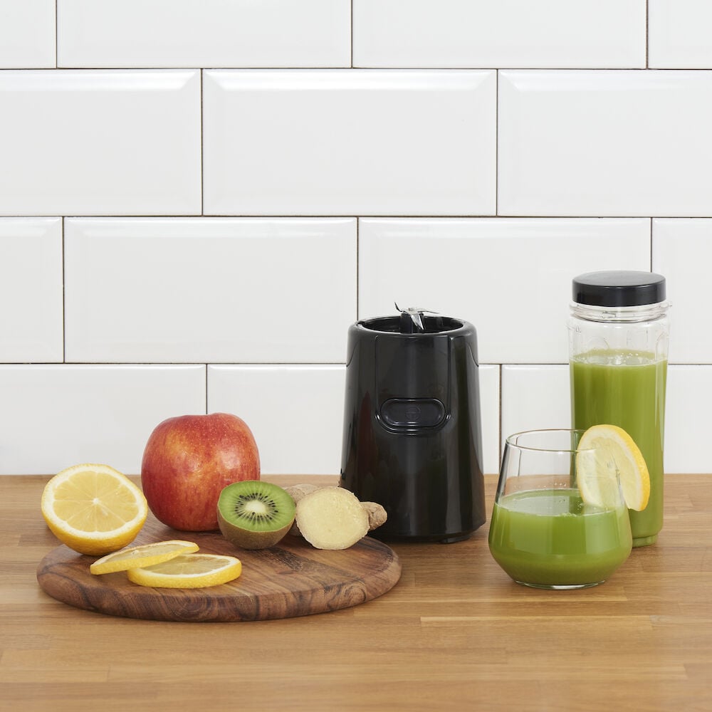 Svart blender med frukter och grön dryck.