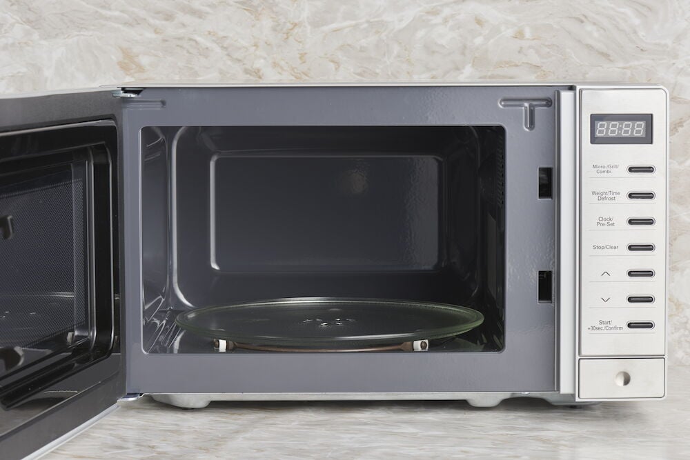 Mikroaaltouuni grillillä, avoin ovi ja lasilautanen.