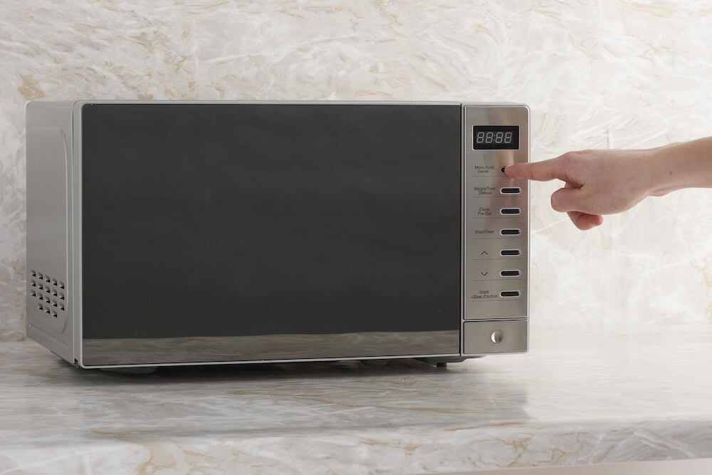 Digitaalinen mikroaaltouuni grillaustoiminnolla marmoripenkillä.
