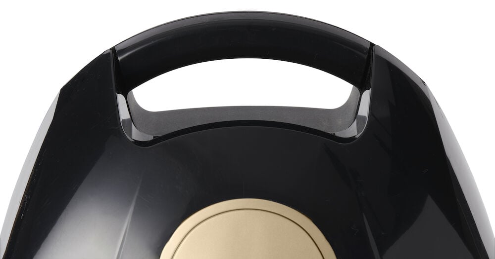 Svart handtag på dammsugare med gulddetalj.