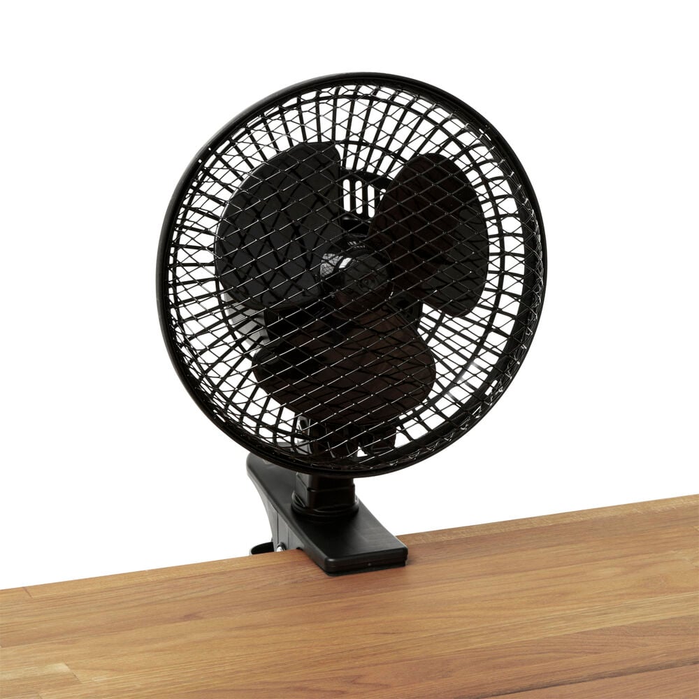 Musta pöytätuuletin, jossa on puristuskiinnike puupöydällä.