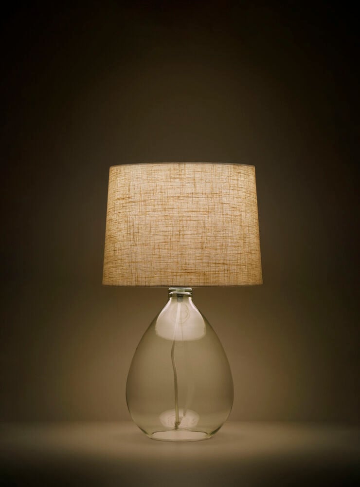 Bordslampa med glasfot och beige linneskärm.