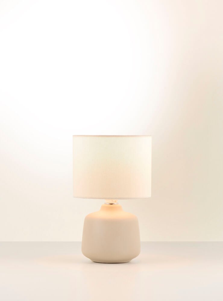 Beige bordslampa med vit cylindrisk lampskärm.